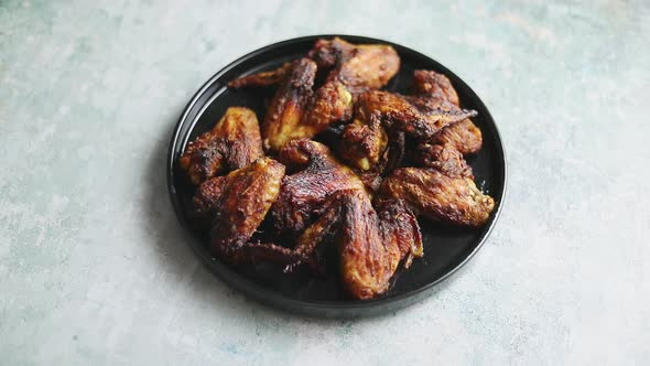 Grilled Chicken Wings on a Black Ceramic Plate. Placed on a Stone