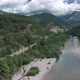 Mountain river with a rocky bank, top view. Green trees and a narrow path meander alongside. - VideoHive Item for Sale