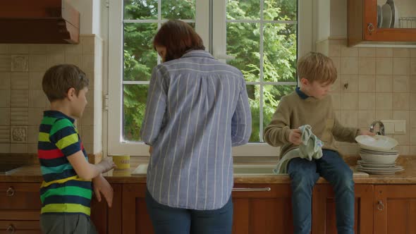 Mother Washing Dishes with Two Sons Nearby