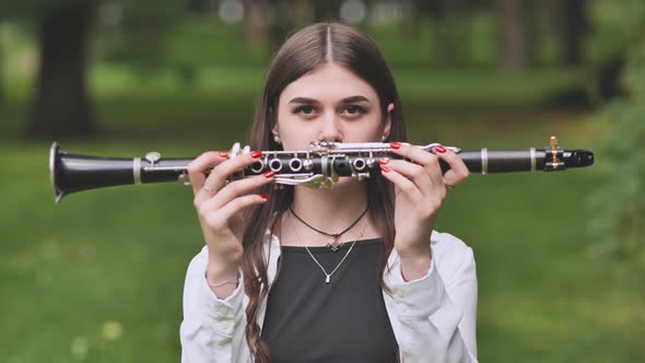 A Young Georgian Girl Holds a Clarinet in Front of Her Face