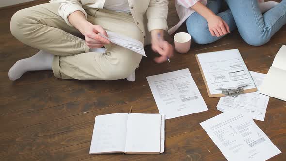 A Young Family Sits on the Floor and Tries to Sort Out the Bills