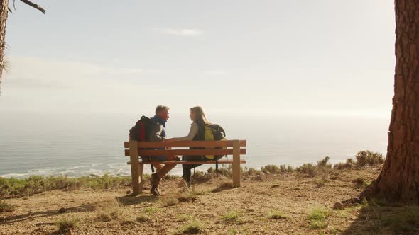Active senior couple sitting on bench in forest
