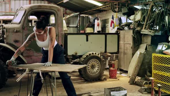 Attractive young woman mechanical worker repairing a vintage car in old garage.