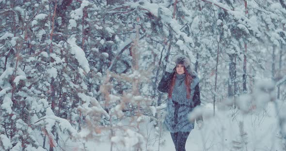 Beautiful and Happy Girl Walks Through the Winter Forest