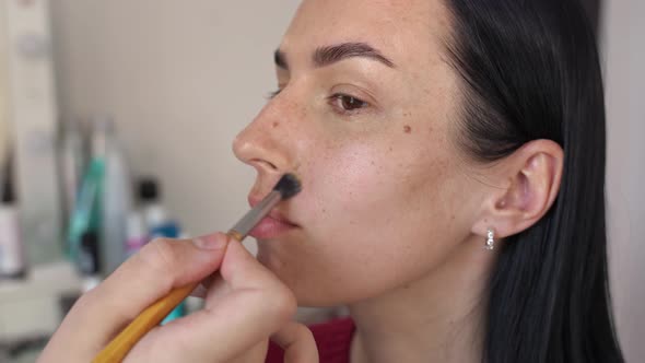 Closeup of a Woman's Face on Which Cosmetics are Applied with a Small Brush