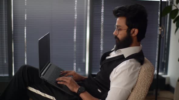 Tired Indian Businessman Working Typing on Laptop Computer Experiences Severe Pain in Neck Rubbing
