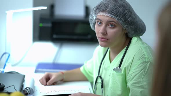 Side View Portrait of Caucasian Gynecologist Telling Bad News to Blurred Woman Holding Head in Hands