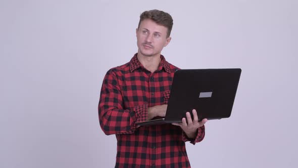 Happy Bearded Hipster Man Thinking While Using Laptop