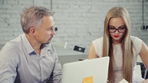 Man and Woman Talking During Working Day at Table with Laptop in Office.