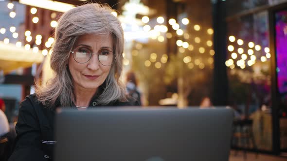 Concentrated Woman Sitting in Cafeteria and Working on Laptop