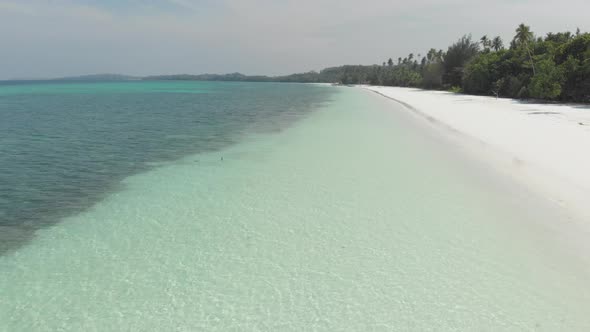 Aerial: Woman on white sand beach turquoise water tropical coastline caribbean sea