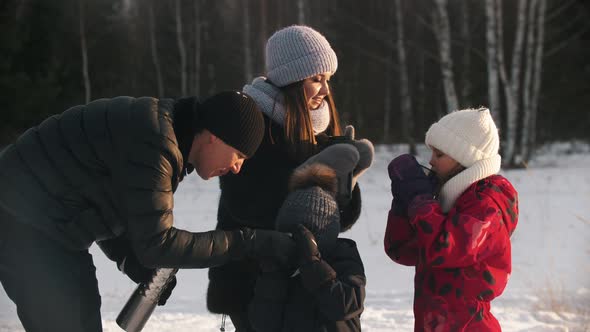 Happy Family of Four People Drinking Hot Drinks From the Termos in Winter Time