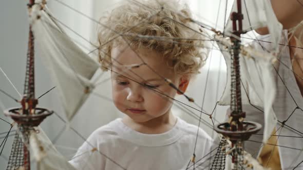 Mother and Baby Boy Playing with Ship Model alt