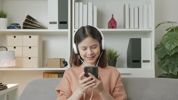 Woman of happy smiling are listening to music from white headphones and using smartphone