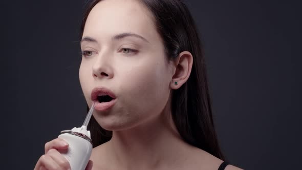 Young Woman Cleaning Her Teeth with Water Flosser in Bathroom