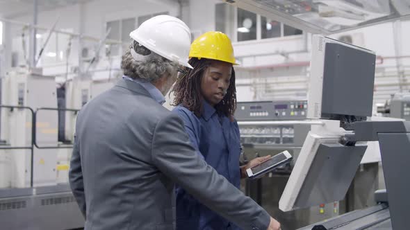 Black Female Industrial Professional Standing at Control Panel