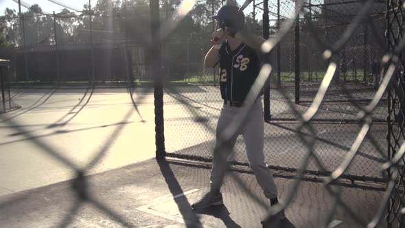 A young man practicing baseball at the batting cages.