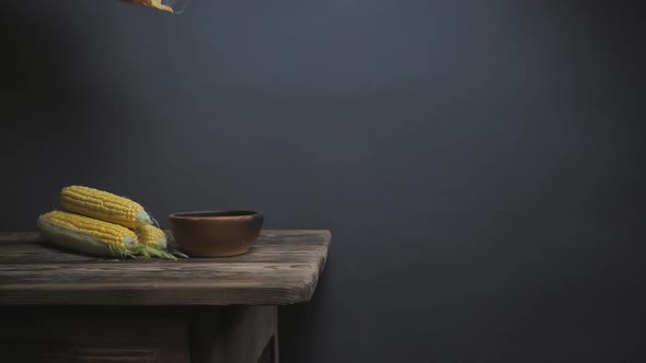 Corn Flakes Fall Into a Bowl on a Wooden Table