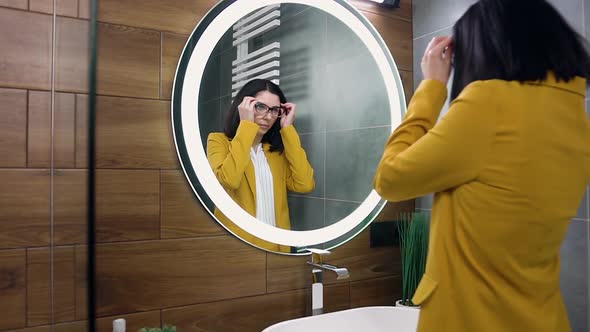 Lady in Olive Suit which Looking Into the Mirror and Putting on Glasses Before Her Exit for Work