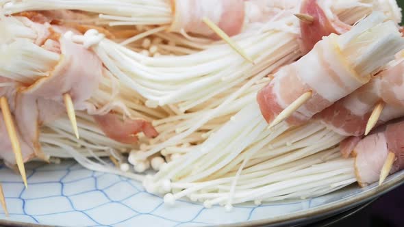 bacon wrapped in golden needle mushroom on dish for barbeque party.