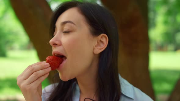 Young Woman Eating Strowberry on Picnic Close Up