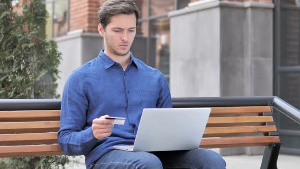 Online Shopping Failure for Young Man Sitting on Bench