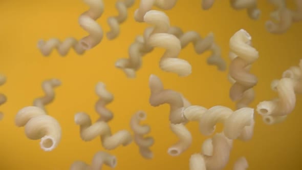  Dry Pasta Cellentani Is Falling Diagonally on the Yellow Background