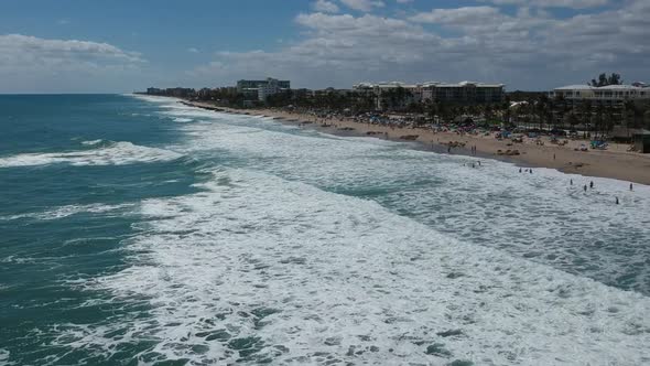 Aerial shot following the shoreline as waves a breaking on the beach