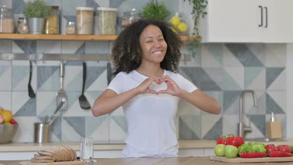 African Woman Making Heart Shape By Hands While in Kitchen