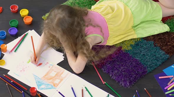 Young child lying on floor and drawing cute picture in illustration school