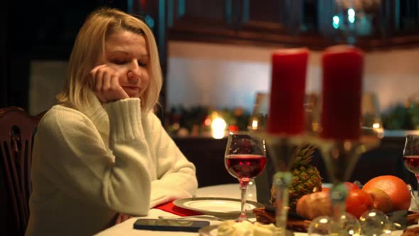 Sad Bored Woman Sitting at Romantic Dinner Table Checking Phone Drinking Wine Thinking