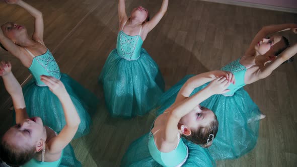 Little Girls in Blue Dresses Sit in a Circle and Stretch Back