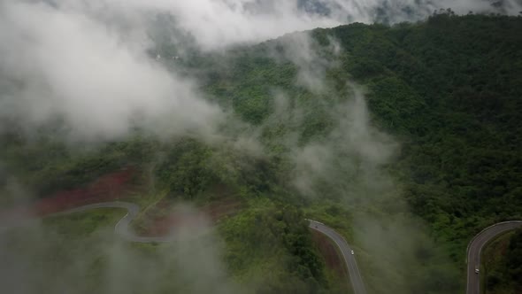 Aerial view flying above lush green tropical rain forest mountain with rain cloud cover during the r