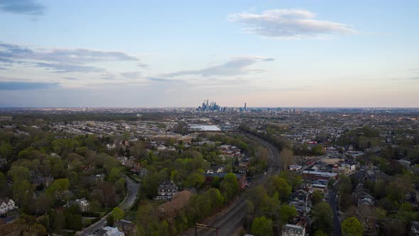Aerial drone timelapse of the Philadelphia skyline with blue skies from the suburbs over green summe