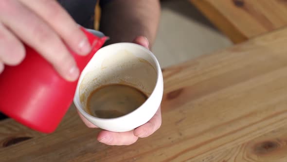 Barista Is Making cappuccino.He Pours Milk Into Coffee. He Is Drawing with Milk.