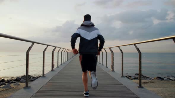 Young attractive athlete running away on a Bridge in the morning from a perspective point of view in