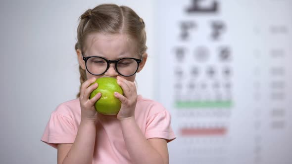 Adorable Girl in Glasses Eating Apple, Natural Vitamins for Eyes, Healthcare