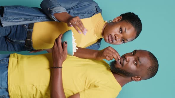 Vertical Video Couple Eating Popcorn Snack From Bowl in Front of Studio Camera