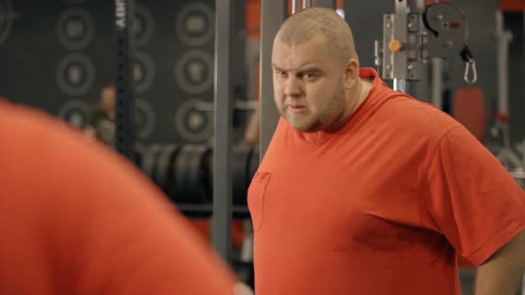 Attractive Young Man Looks at Himself in the the Sport Gym