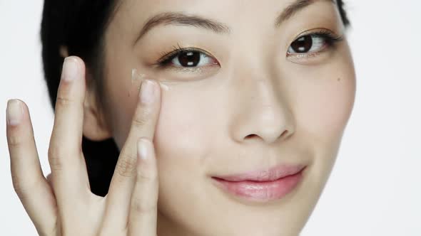 Young woman applying eye cream