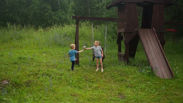 Little Girl Gives Bouquet to Younger Brother on Playground