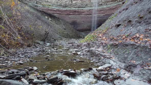 Rocky mountain valley bedrock with small skinny waterfall, low to ground gimbal