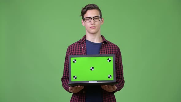 Young Handsome Teenage Nerd Boy Showing Laptop