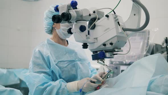 Female Surgeon Uses Devices While Working with Patient's Eyes.