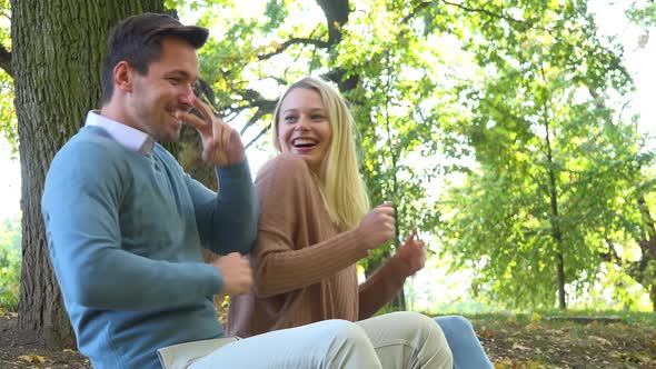 A Man and a Woman Sit in a Park on a Sunny Day and Dance