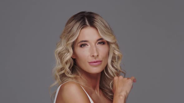 Studio portrait of young and beautiful blond woman over grey background.