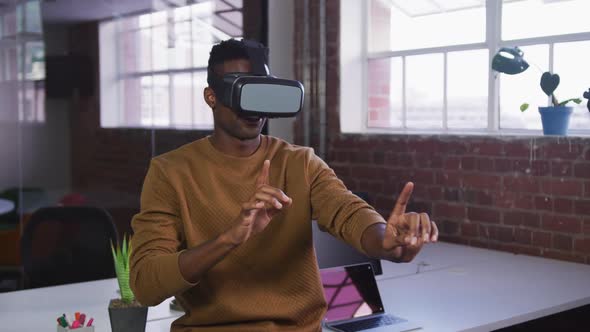 African american businessman sitting on desk using vr headset and gesturing