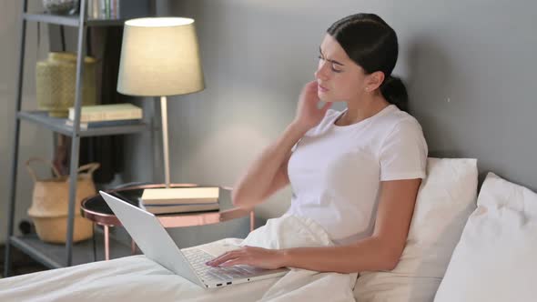 Latin Woman with Laptop Having Neck Pain in Bed