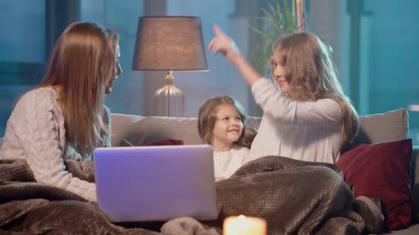 Two Girls and Their Mother Sitting on Couch with Laptop