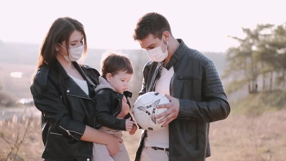 Happy Parents and a Cute Son Are Playing Football Outside